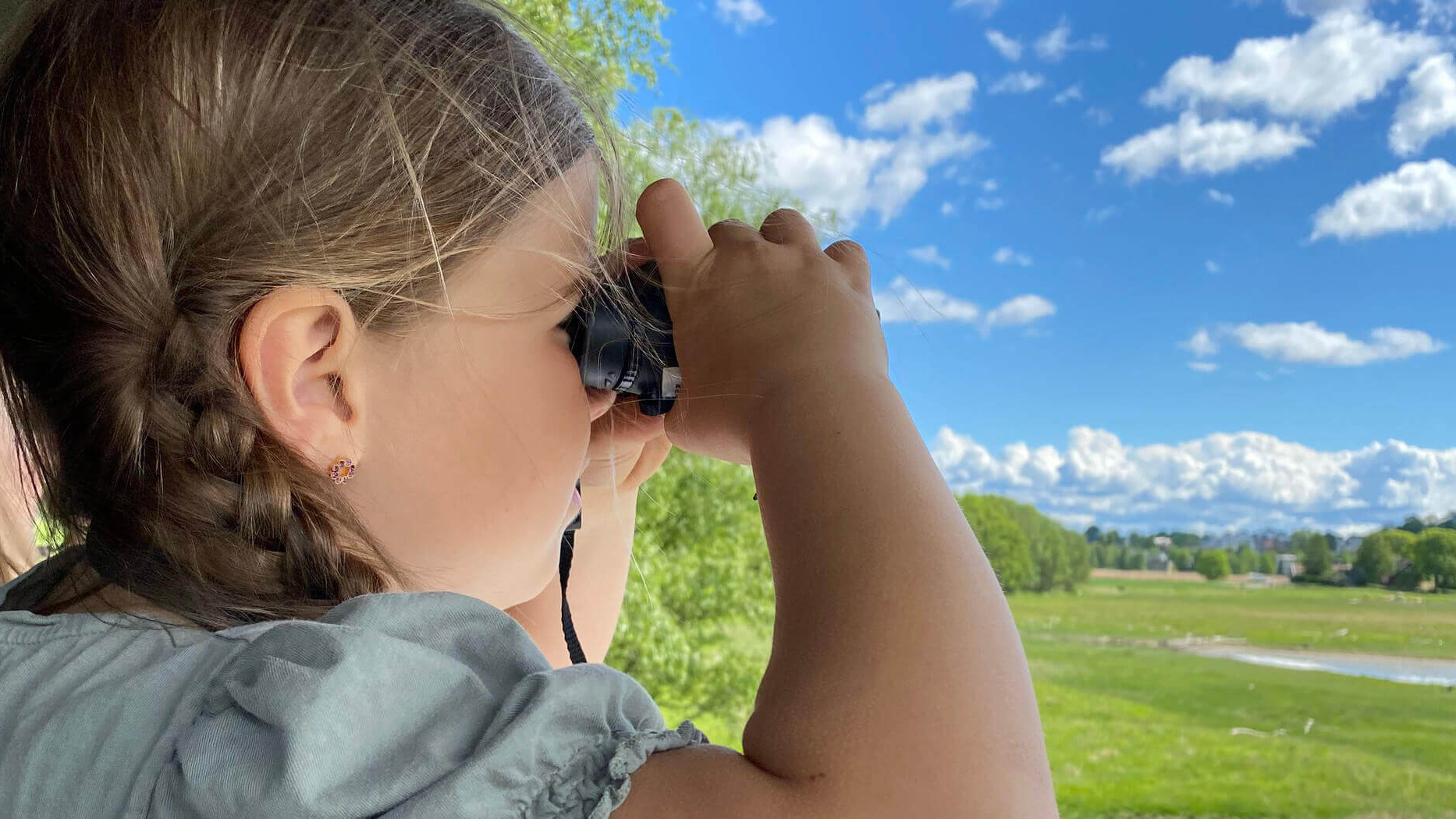 Jente som ser i kikkert ut over våtmarkene. Foto: Aileen Gundersen