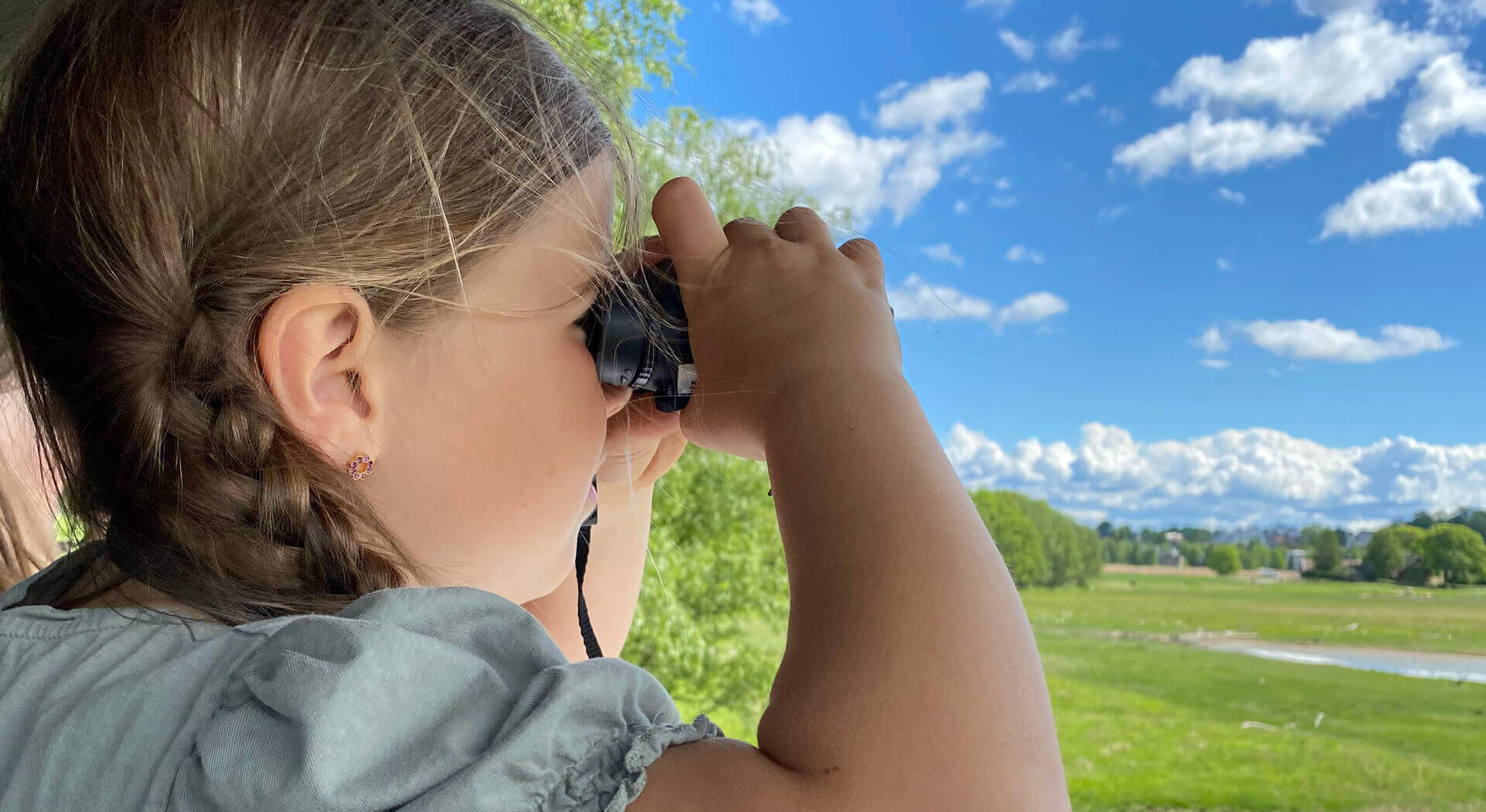 Jente som ser i kikkert ut over våtmarkene. Foto: Aileen Gundersen