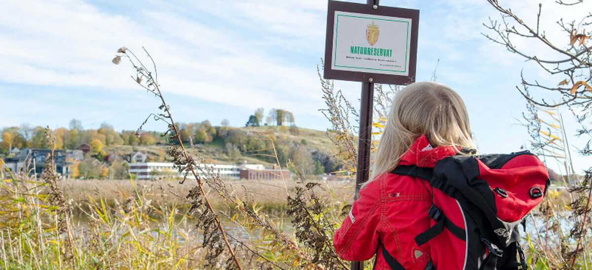 Jente foran verneskilt og våtmark